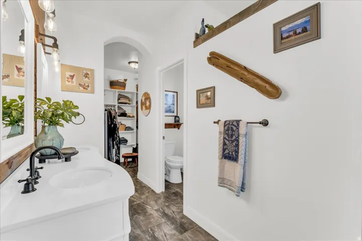 Vanity with white countertop, dark-finish faucet, and wood-framed mirror