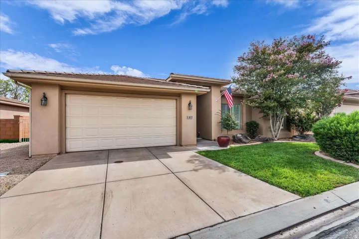 Stucco exterior with a two-car garage, concrete driveway, and front lawn