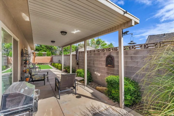 Covered patio with concrete flooring, block wall fencing, and low-maintenance landscaping
