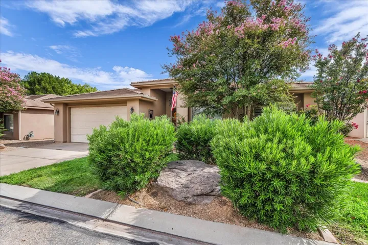 Stucco exterior with a tiled roof, integrated garage, and mature landscaping