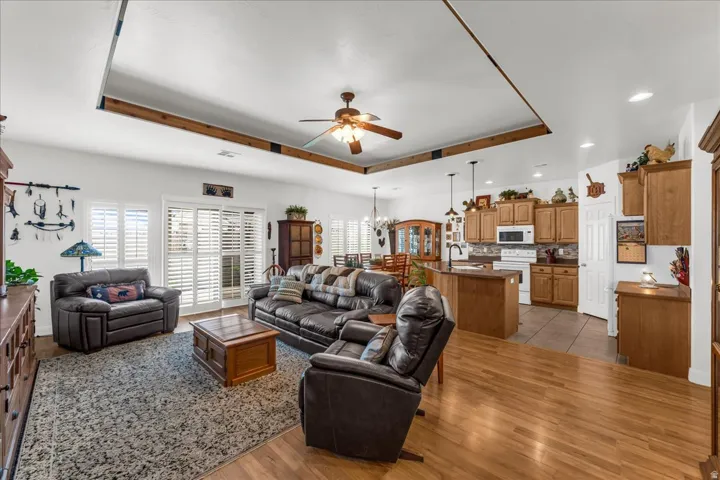 Open-concept living space featuring wood-finish flooring, a kitchen island with seating, wood cabinetry, and a ceiling fan