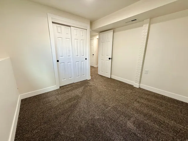 Plush carpeting, white walls, and a bi-fold closet with black hardware