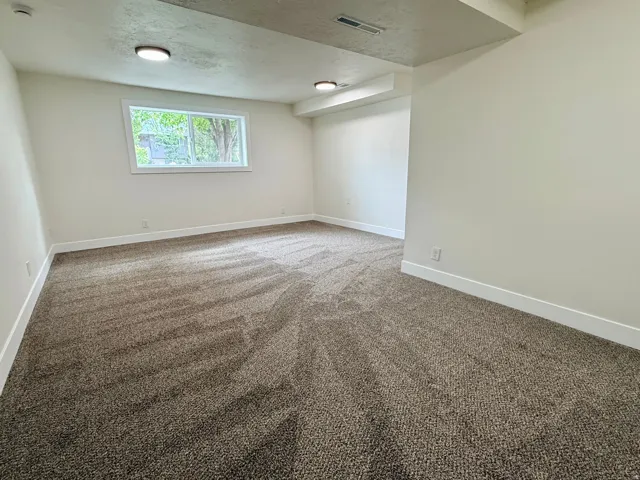 Neutral tone wall paint, recessed lighting, white trim, textured carpeting, and a window with natural light