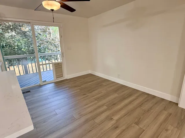 Wood-finish flooring, white walls, and a sliding glass door with an exterior deck