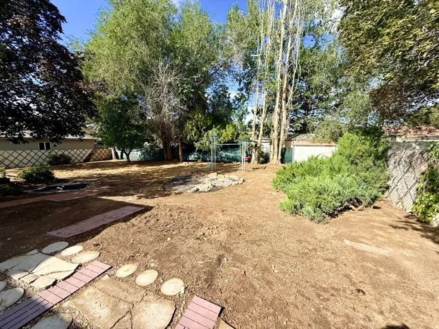 Expansive yard with mature trees, established shrubs, a concrete patio, and brick paver pathways