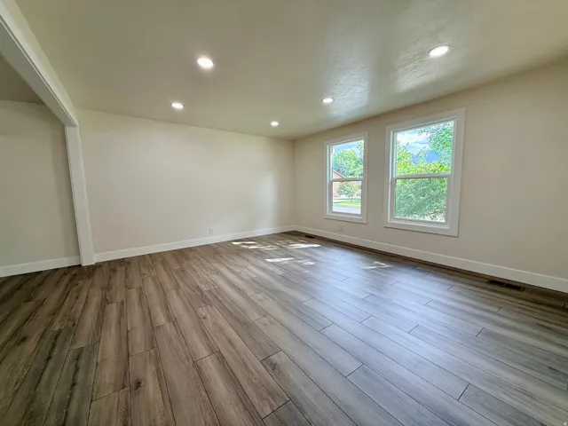 Wood-finish flooring, recessed lighting, and two windows with white trim