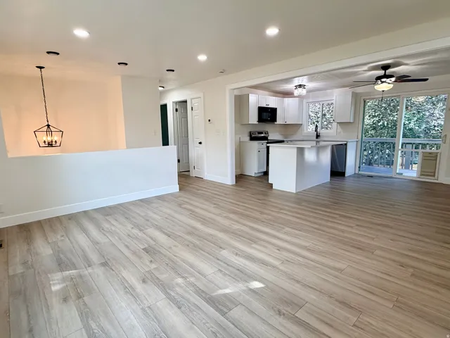 Open-concept living space featuring light wood-finish flooring throughout, recessed ceiling lighting, and a large island with white cabinetry and countertop workspace