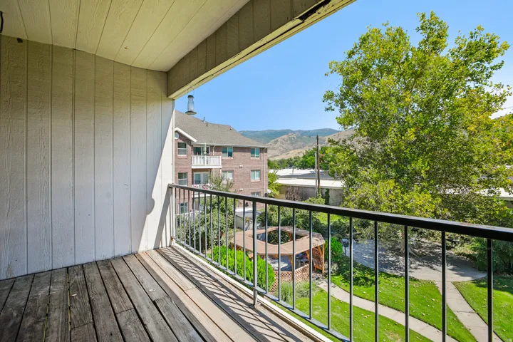 Private balcony with wood-finish flooring and metal railings
