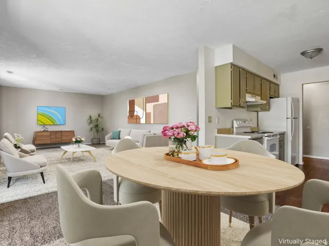 Open-concept dining area featuring an oval wood-finish table with a fluted pedestal base