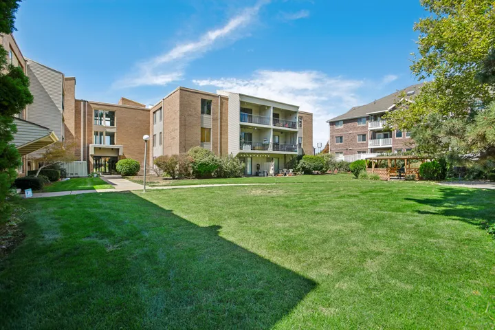 Expansive green lawn, brick exterior building with balconies, and a wooden gazebo