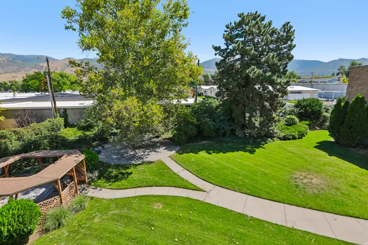Expansive lawn area with mature trees, curved concrete pathways, and a wood-frame gazebo