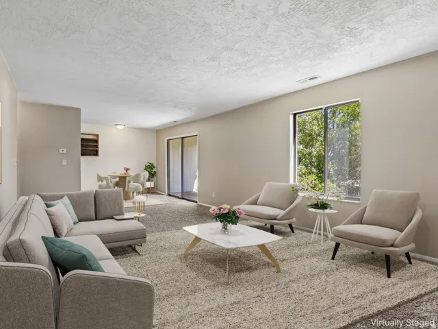 Neutral wall tones with textured ceilings, carpet flooring, a large window, and sliding glass doors