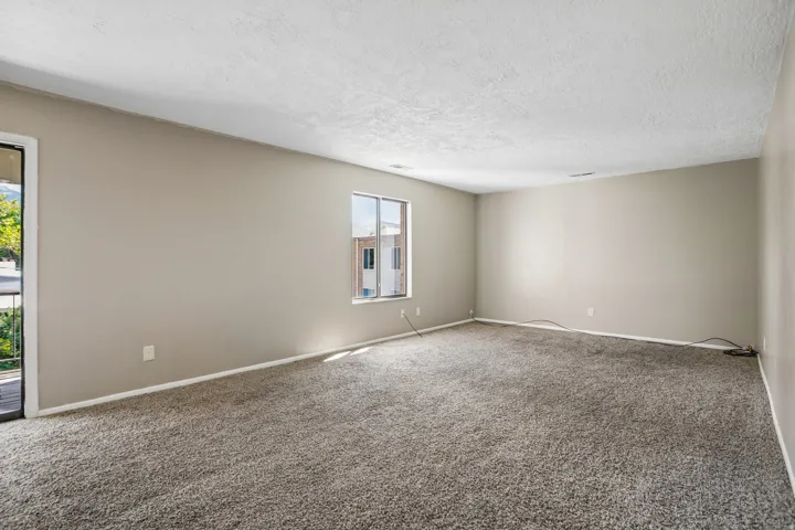 Spacious room with neutral wall tones, textured ceiling, and carpeting