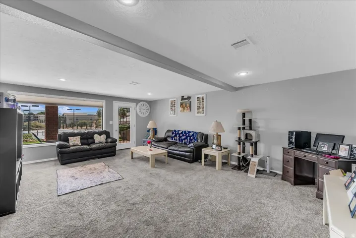 Spacious living area featuring light gray carpeting, recessed lighting, a large picture window, and a glass-paneled exterior door
