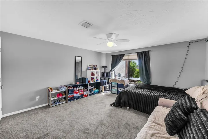 Carpeted room with a ceiling fan, light gray walls, and a window with dark curtains