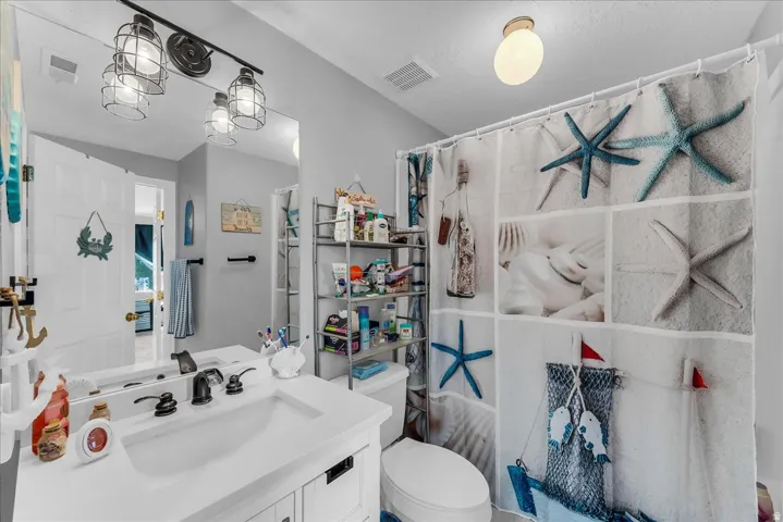 White vanity with integrated sink, black faucet, and full-width mirror