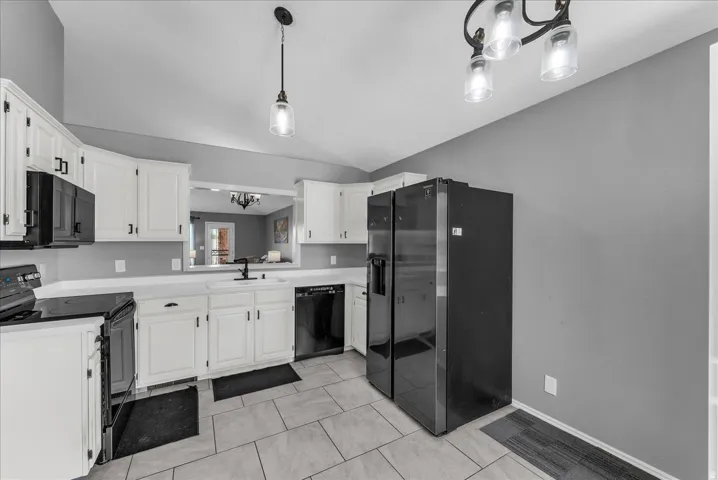 Kitchen featuring white cabinetry, black hardware, an undermount sink with a matte black faucet, and tile flooring