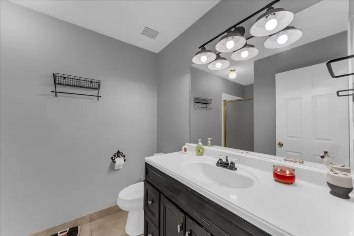 Bathroom featuring a single vanity with dark cabinetry, white countertop, and an integrated sink