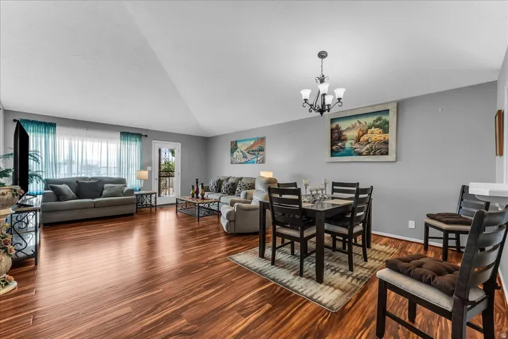 Vaulted ceiling, wood-finish flooring, white trim, and a glass-paneled door