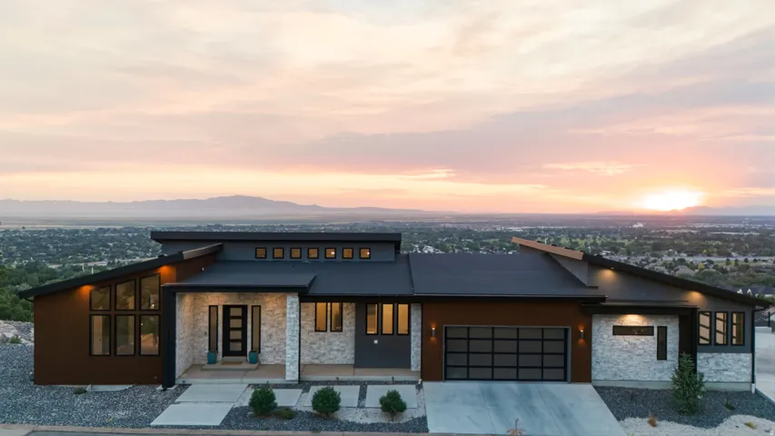 Modern architectural design featuring varied rooflines, stone and wood-tone exterior accents, a full-lite entry door, and a glass-paneled garage door
