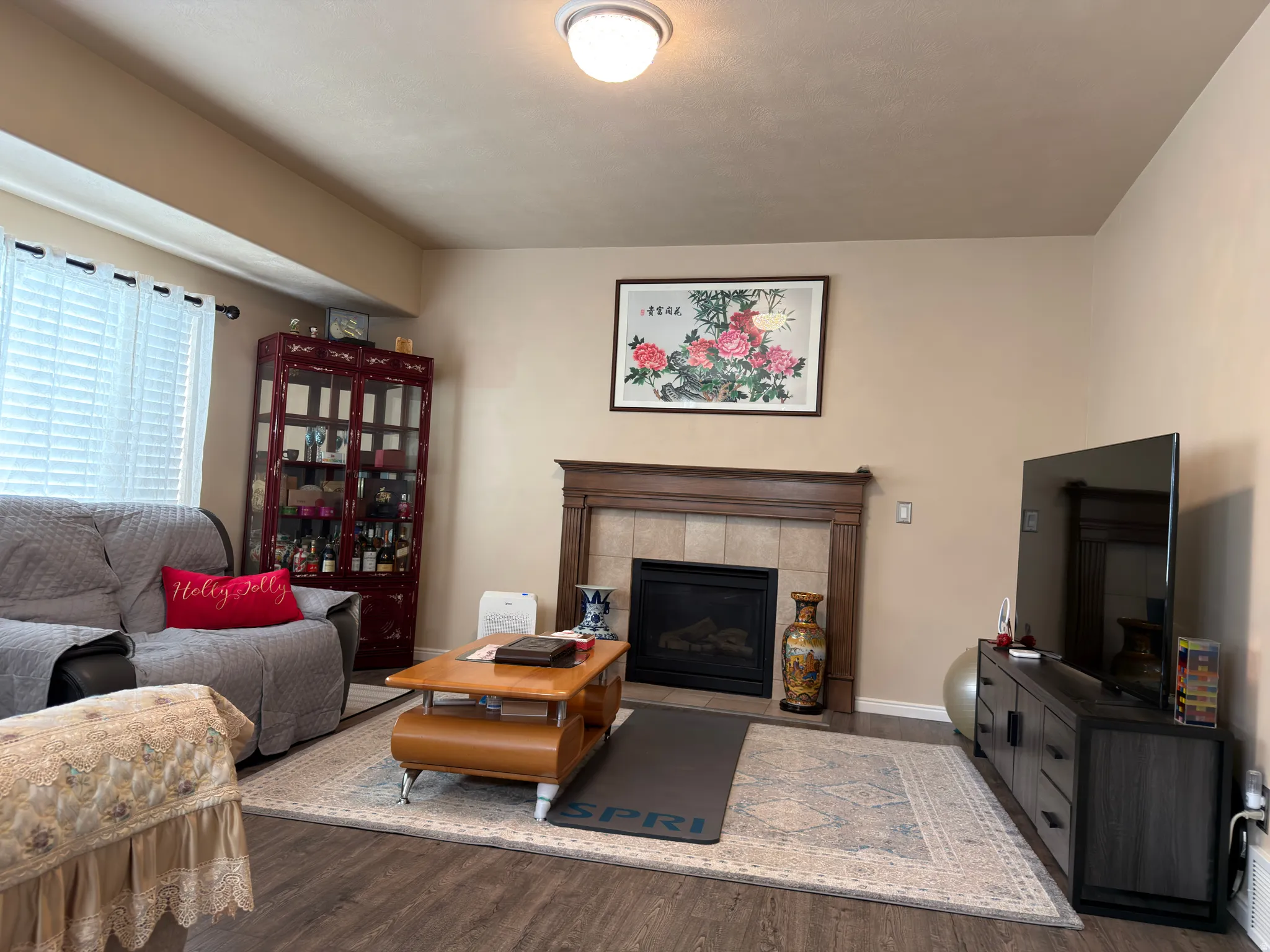 Fireplace with a wood mantel and tile surround, wood-finish flooring, and a ceiling-mounted light fixture