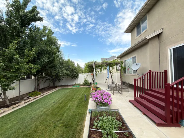 Expansive backyard with a manicured lawn, established trees, and a concrete patio