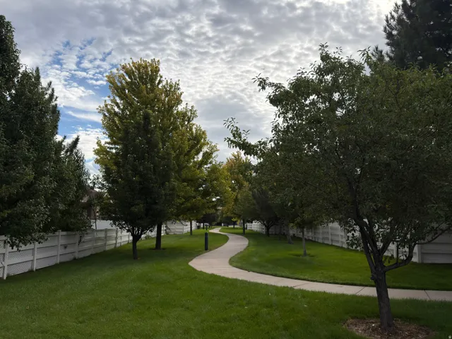 Meandering pathway, surrounded by manicured lawns, mature trees, and privacy fencing