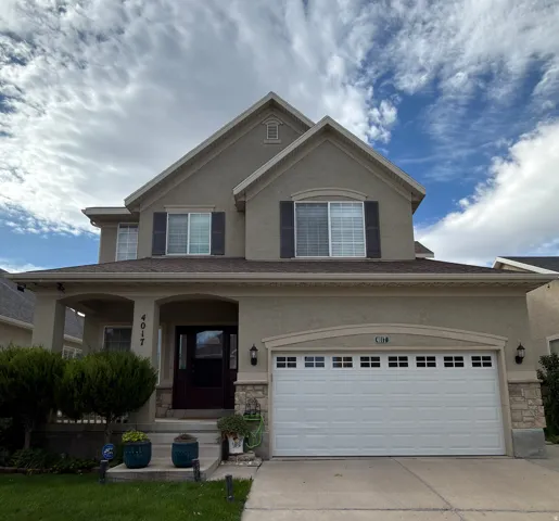 Stucco exterior with a covered porch, stone accents, attached two-car garage, and a dark-stained entry door