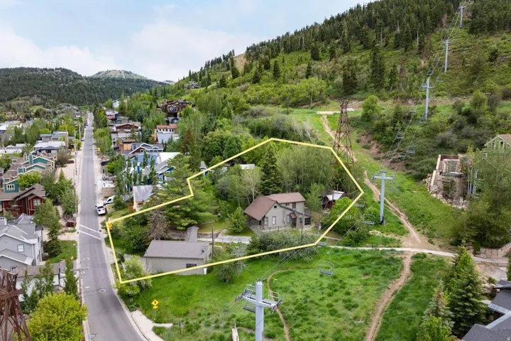 Property situated on a hillside with surrounding greenery, featuring an established residential street
