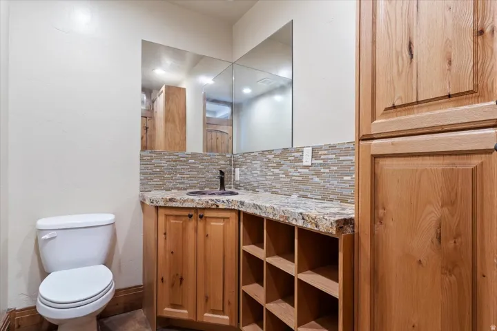 Built-in wood cabinetry, integrated shelving, and a dark basin sink set in a light-toned countertop with a tile backsplash