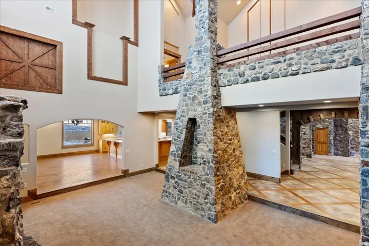 Two-story stone fireplace, vaulted ceilings, upper-level wood railing, wood-finish flooring, and arched doorways