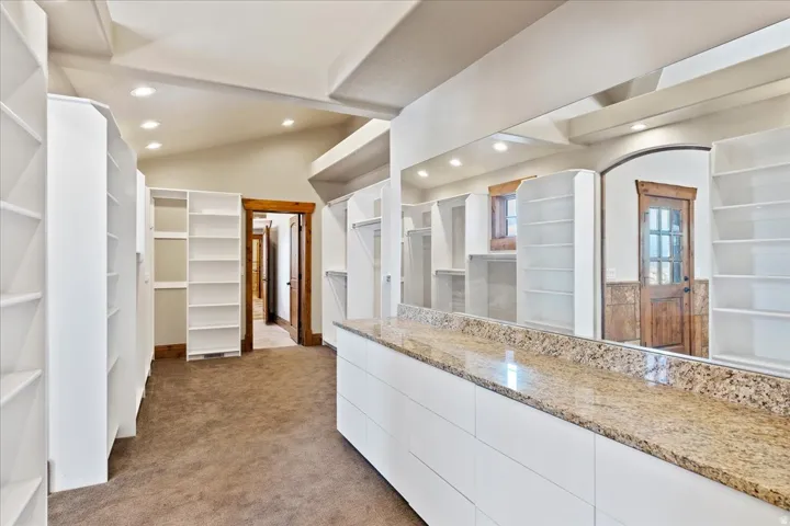 Built-in storage solutions with white shelving, a granite-finish countertop, and recessed lighting