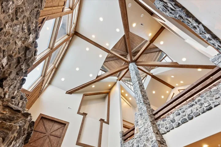 Vaulted ceilings featuring exposed wood beams, stone accents, recessed lighting, and expansive clerestory windows