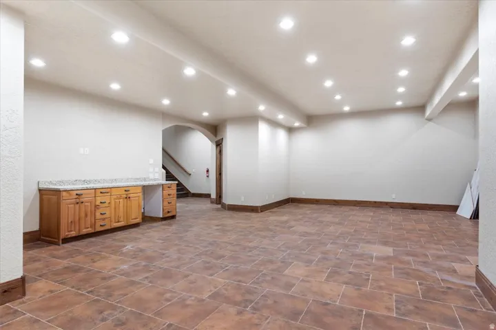 Spacious room featuring tile flooring, recessed lighting, and a built-in wood cabinet with a light-colored countertop