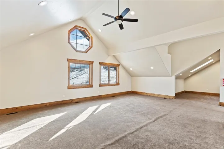 Vaulted ceiling with recessed lighting and a ceiling fan, featuring a large octagonal window and two rectangular windows with wood trim
