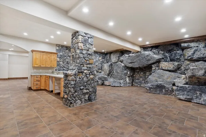 Stone-clad accent wall and column with recessed lighting, integrated wood-finish cabinetry, and tiled flooring