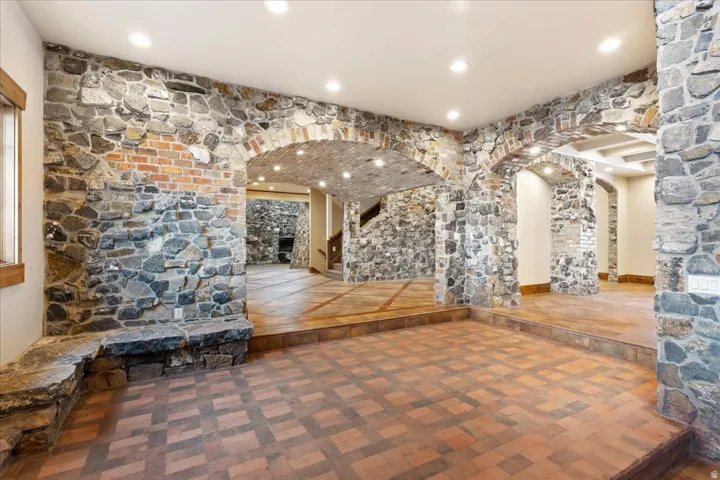 Stone and brick wall accents, recessed lighting, arched doorways, tiled flooring, and a built-in stone bench