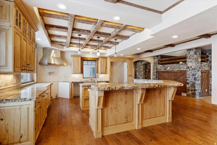 Kitchen with wood-finish flooring, custom wood cabinetry, and granite countertops