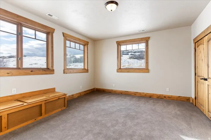 Built-in wood bench with storage, wood-trimmed windows with mullions, wood baseboards, wood panel doors with black hardware, and gray carpet
