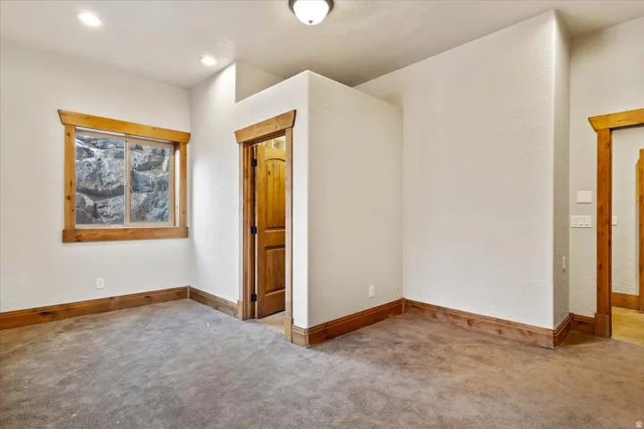 Neutral wall finishes, wood-trim window and door frames, wood-panel door, recessed ceiling lighting, and carpeted flooring
