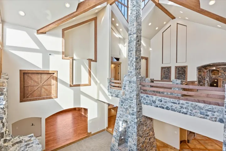 Two-story stone fireplace, cathedral ceilings, exposed wood beams, skylights, and a stone and wood-finish railing