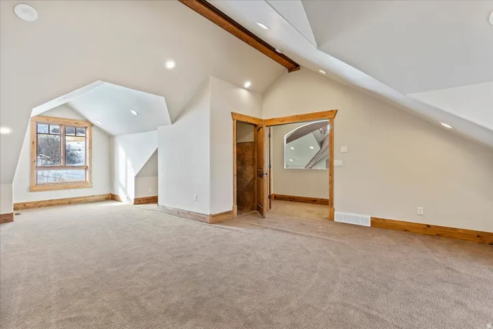 Vaulted ceiling featuring exposed wood beams, recessed lighting, and natural wood trim accents