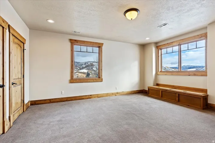 Carpeted room featuring natural wood trim, recessed lighting, a built-in window bench, and two windows