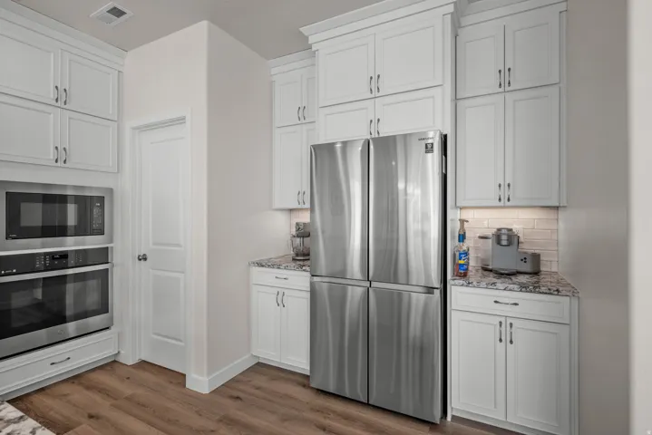 Kitchen featuring white shaker-style cabinetry, granite countertops, and wood-finish flooring