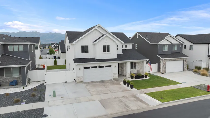 White siding exterior with black-framed windows, stone facade accents, and a two-car garage