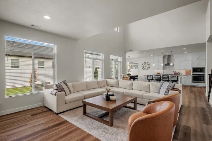 Open-concept living area featuring wood-finish flooring, high ceilings, large windows, and recessed lighting