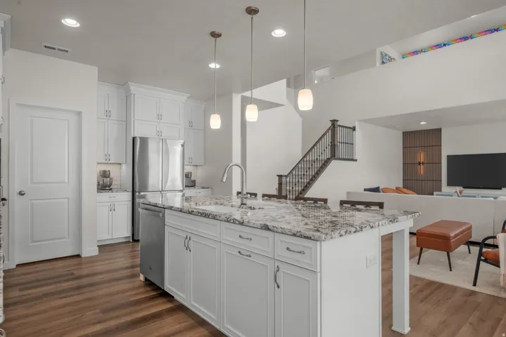 Kitchen featuring white cabinetry, stainless steel appliances, a center island with a speckled countertop, and wood-finish flooring