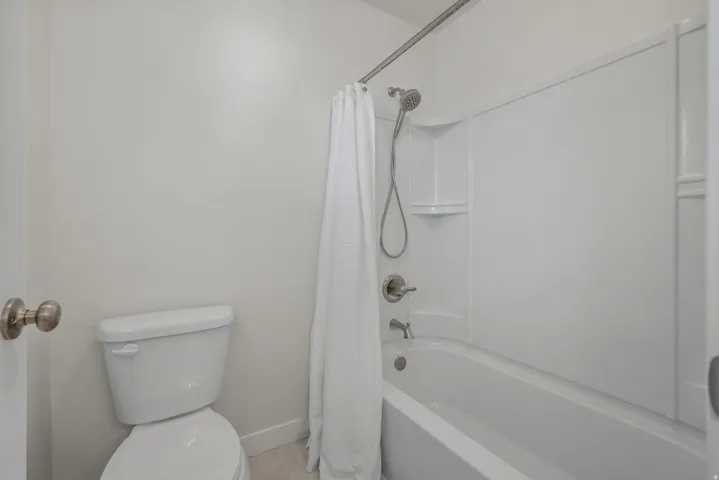 White tub/shower combination with integrated shelving and brushed nickel fixtures