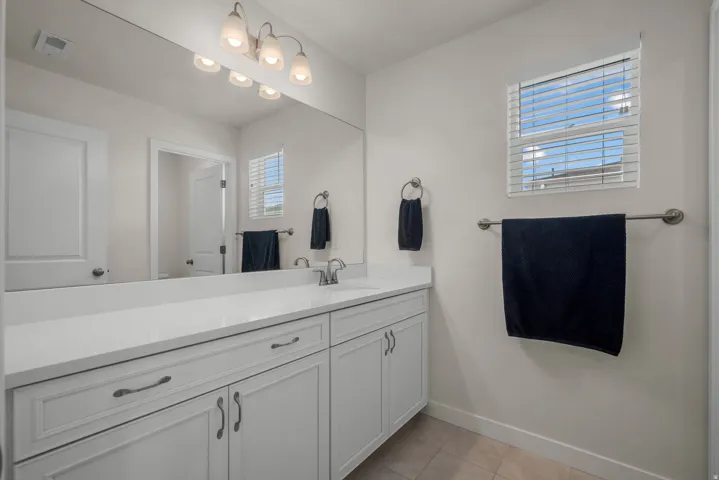 Spa-inspired primary bathroom featuring a dual-sink vanity with white cabinetry, quartz countertop, and brushed nickel hardware