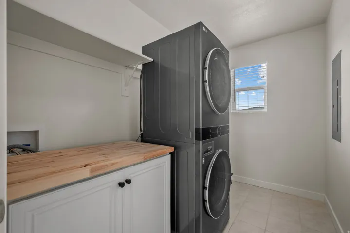 Built-in cabinetry with a wood-finish countertop, white shelving, and tiled flooring